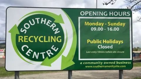 SCAS Picure of the recycling sites sign in Port St Mary. It reads it's opening times and logo to the left.