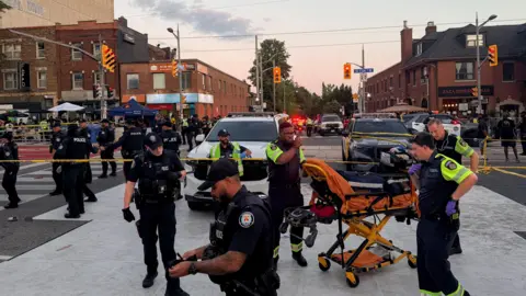 Reuters Police officers stand guard as emergency workers respond at the site of a deadly shooting at a salsa-themed street festival in Toronto.