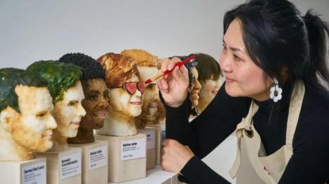 Michelle Wibowo looking at the celebrity heads made out of sushi
