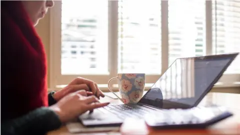 PA Media A woman works from home on a laptop