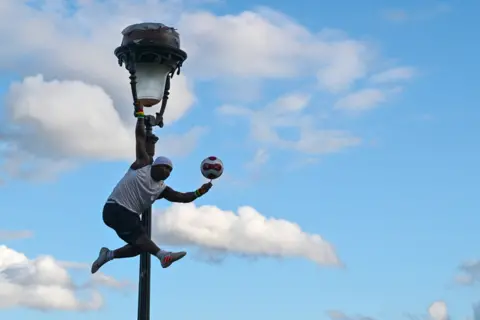Miguel Medina/AFP Guinean performer Iya Traore with a ball up a lamp post in Montmartre in Paris, France - Friday 22 September 2023