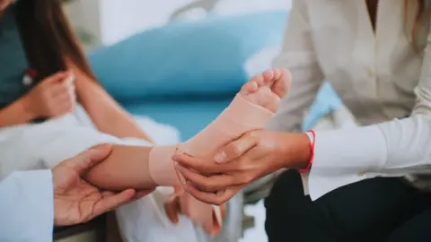 child gets checked over as health professional examines a foot in a bandage