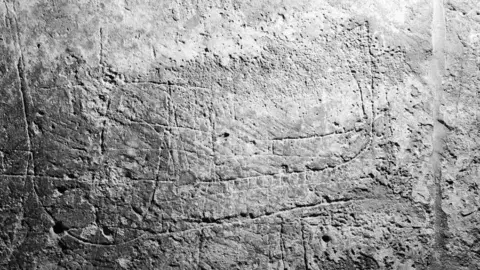 Ashley Taylor, Push Creativity UK Close up image of the Viking longship carved on a wall inside Stow Minster. The etching includes a depiction of a sail, with oars protruding from the side of the vessel.