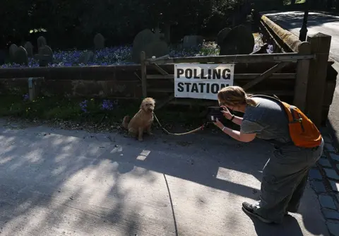 EPA A voter takes a photograph of their dog outside a polling station in Runcorn, Britain, 1 May 2025. 