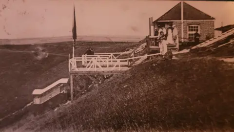 Supplied The side of a hill. There is a building on it. 