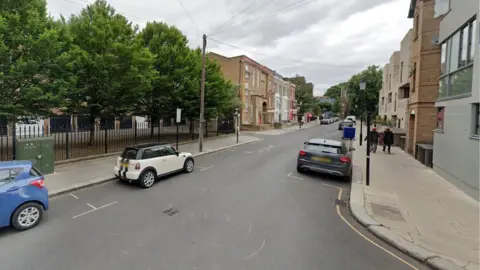 Southern Row street view shows three parked cars and two pedestrians on street with trees, lamps and houses