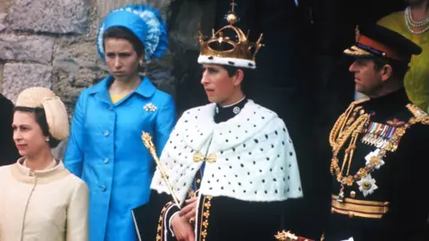 Getty Images Prince Charles, wearing the crown after being invested with the title Prince of Wales, on a balcony with The Queen and Prince Philip