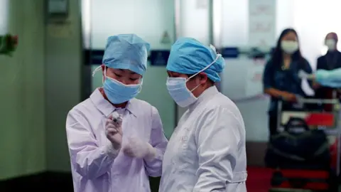 Getty Images Nurses check a thermometer reading in the departure hall of the Beijing's Capital Airport April 28, 2003