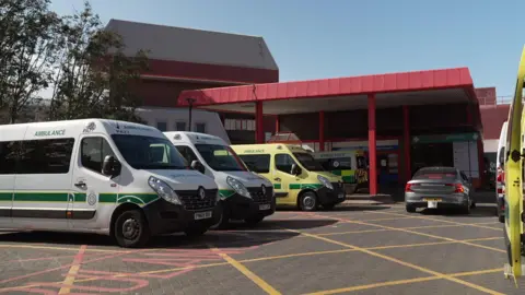 The entrance to Southport & Formby District Hospital showing an red brick building and a number of ambulances parked outside