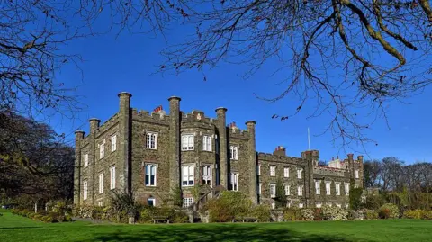 MANX SCENES The exterior of the nunnery a grand brown three-storey building with a large field in front on a clear blue day.