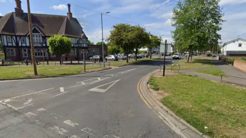 Junction of Bellfield Avenue and Holderness Road. A large mock timber pub the Four in Hand stands on the corner with trees, cars and grass verges in the background