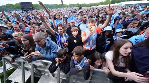 PA Media A players view from the stage at War Memorial Park. Thousands of fans are behind barriers, looking towards the stage