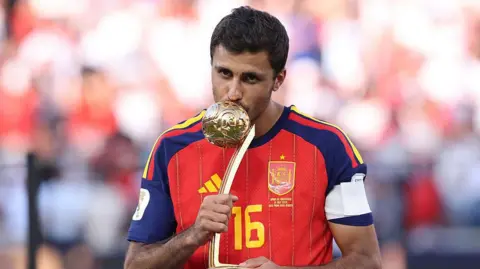 Rodri kissing the World Cup Golden Ball award