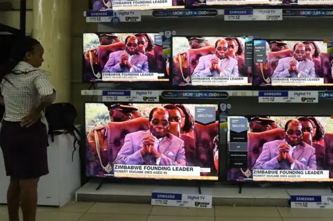 AFP A Kenyan woman watches news with the headline on the death of former Zimbabwean president Robert Mugabe, at an electronics shop in Nairobi on September 6, 2019