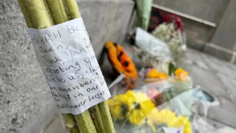 Close up of note and stem of flowers leaning on grey stone