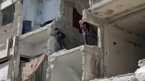 AFP Syrian children look down from a destroyed building following air strikes on the rebel-held town of Douma, in the Eastern Ghouta (25 March 2018)