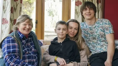 PA Media Ukrainian refugees Yaroslav Kryvoshyia (right) and Irina Kryvoviaz (second right) with her son Sasha and their host Sarah Allen-Stevens (left)