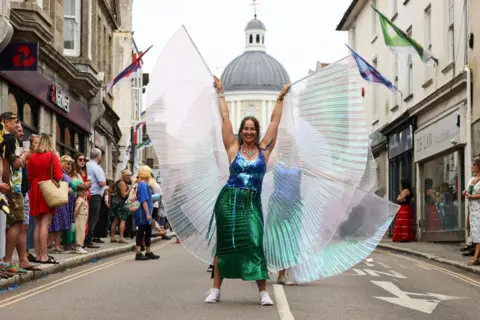 Penzance Council A woman in a blue and green sequined outfit and giant wings