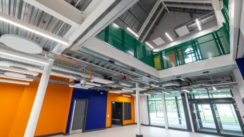 Blackburn with Darwen Borough Council The interior of the building, with a mezzanine seen on the first floor. Large entrance doors and windows can be seen. The walls are painted in orange and blue.