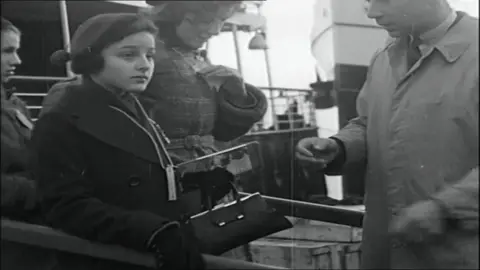 British Pathe Children holding their passes and belongings leaving a boat and waiting to be checked