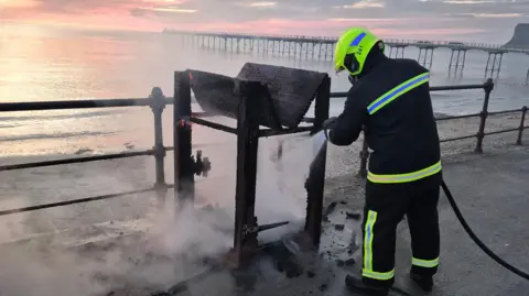 Cleveland Fire Brigade Firefighter extinguishing bin fire on Saltburn promenade