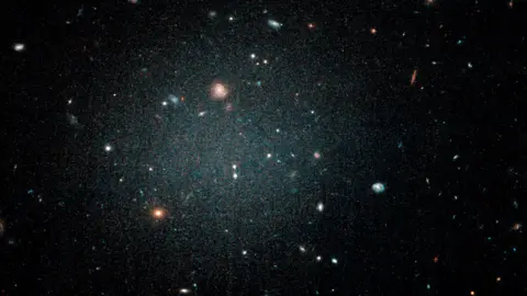 NASA/ESA/P. van Dokkum A diffuse fuzzy blob with other galaxies visible behind it