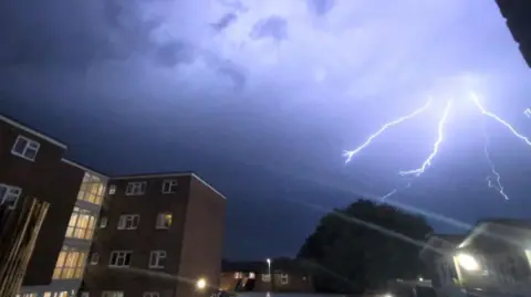Chelsea Claw Lightning lights up the sky blue above blocks of flats.
