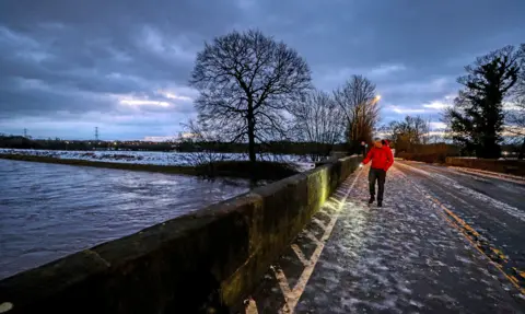 PA Media A council worker in Didsbury, Manchester, checks a bridge for damage after heavy rainfall, on 21 January 2021