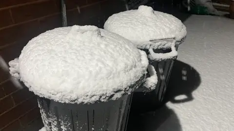 Two black bins covered in snow