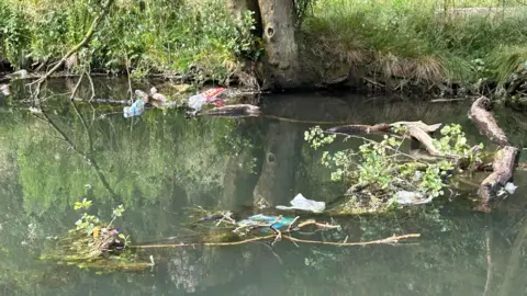 Andrew Trickey Plastic bottles and other rubbish floating in the river