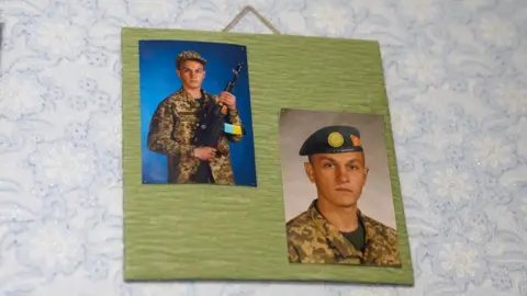Two photos of Lera's brother in uniform hang on the wall