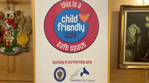 A large white sign with the "Child Friendly Cov" at the top.