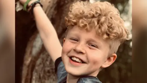 FAMILY HANDOUT A photo of Harry Moss smiling while hanging onto a tree branch.