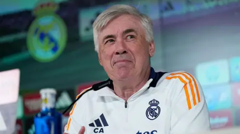 Carlo Ancelotti wearing a white Real Madrid top