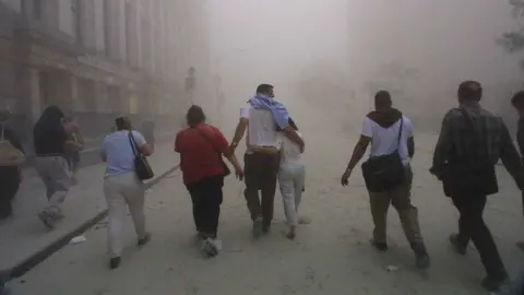 As imagens gatety escaparam com dez homens e mulheres desabaram em 11 de setembro de 2001, com o colapso de uma das torres do World Trade Center em Nova York. A calçada debaixo dos pés é coberta pelos detritos e o ar está cheio de fumaça. 