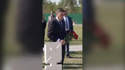UK Prime Minister Andy Burnham wearing suit and holding bouquet of red roses