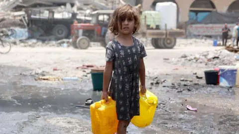AFP A Palestinian girl carries water containers in Jabalia refugee camp, in the northern Gaza Strip (3 June 2024)