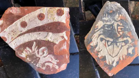 English Heritage Two irregular brown tiles with white patterns on them, depicting animals