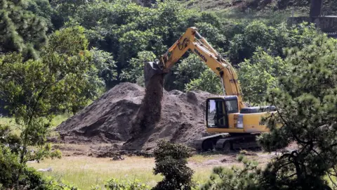 AFP A digger uncovering the mass grave in Jalisco, Mexico, earlier in September