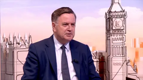 Mel Stride wearing navy blue suit during in-studio interview