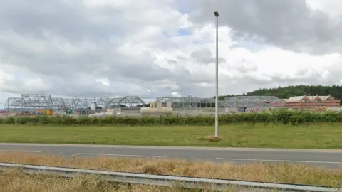 Google A construction site with iron frames, seen from the other side of a dual carriageway