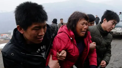 Relatives of trapped coal mine workers are carried away from the site of a flooding accident at the coal mine, sitting astride Xiangning County of Linfen City and Hejin City of Yuncheng City, Shanxi province March 29, 2010. 