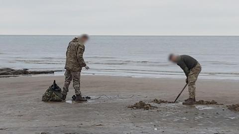 Soldiers work to destroy the mortar rounds on the beach