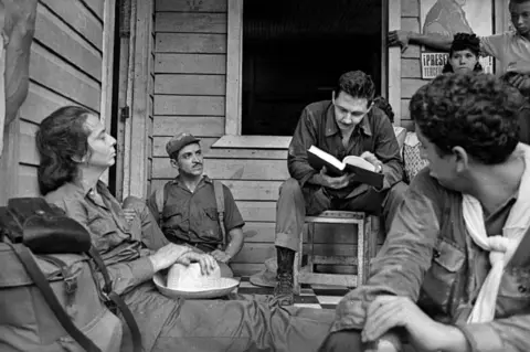 Getty Images Raúl Castro talking with a family in Cuba in 1964. (Photo by Gilberto Ante/Roger Viollet via Getty Images)