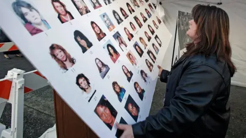 AFP Court official Kathryn Quon puts up a poster of missing women outside the court where the trial for accused serial killer Robert Pickton, 2007