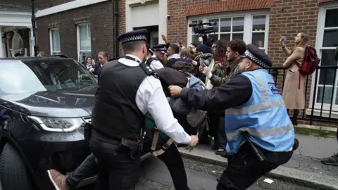 PA Media Police officers remove a protester trying to block Sir Keir's car following the speech