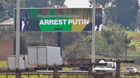 AFP A billboard urging South Africa's president to arrest Mr Putin if he comes for the Brics summit - March 2023