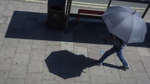 Getty Images person sheltering under umbrella