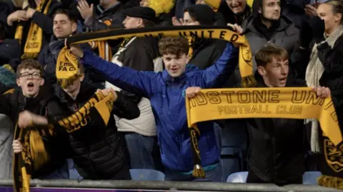 BBC/ANDREW MARSHALL Maidstone fans holding scarves supporting the team