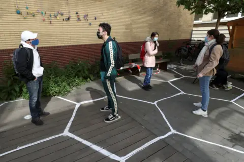 Reuters Students stand separately in designated hexagon shapes on the floor